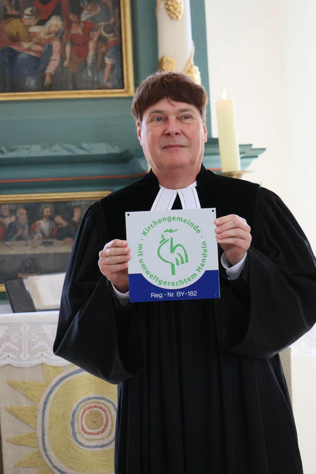 Pfarrer Martin Bauer zeigt stolz die Plakette des "Grünen Gockel". Foto: Matthias Hofmann
