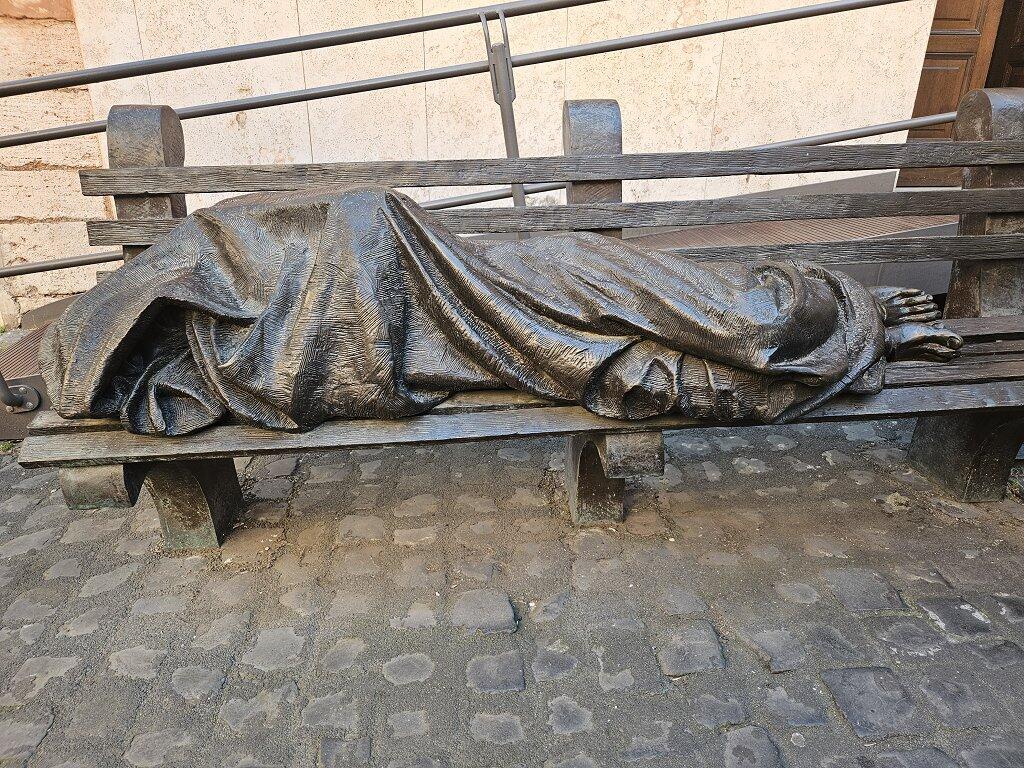 Vor der Kirche von Sant’Egidio liegt "homeless Jesus" auf der Bank