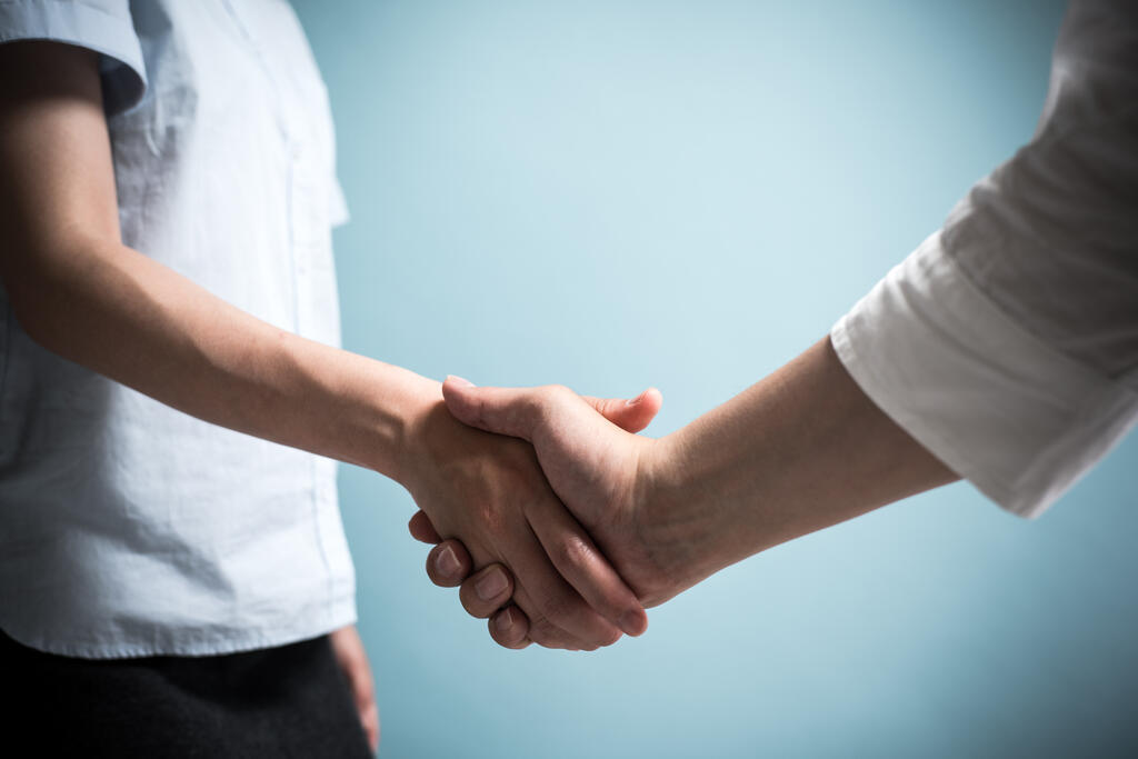 Zwei Menschen geben sich die Hand