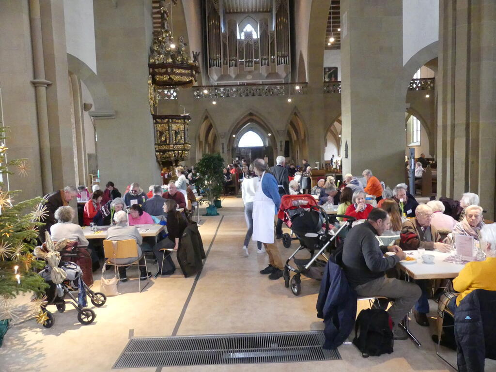 Menschen sitzen gemeinsam an Tischen in der Vesperkirche (Foto von 2014)