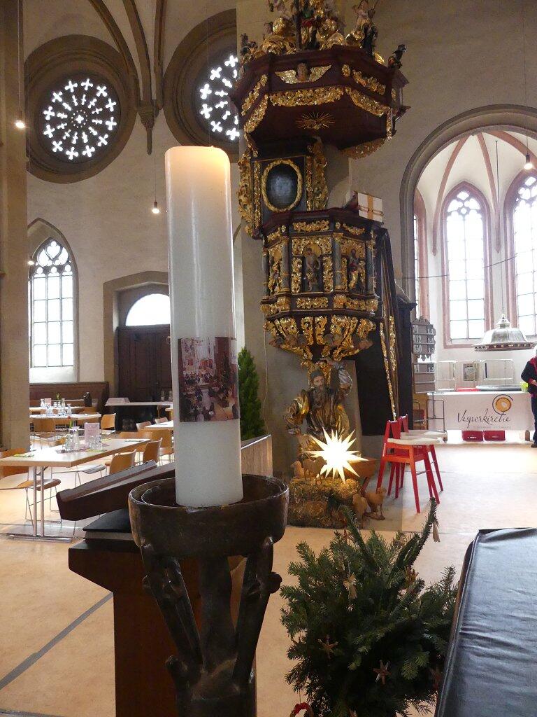 Ein Weihnachtsstern leuchtet unter der Kanzel während der Vesperkirche. Im Vordergrund die Vesperkirchenkerze.