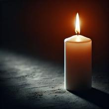 Eine einfache Kerze wirft Licht auf den Boden. Der Hintergrund ist schwarz.