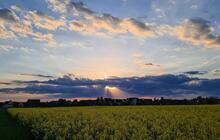 Sonnenstrahlen brechen durch eine dunkle Wolkenfront, der Rest des Himmels ist hell mit einzelnen weißen Wolken.