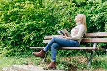 Eine Frau im Wald betet und liest in der Bibel.