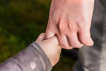 Eine Erwachsenenhand hält eine Kinderhand.