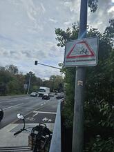 Am Ende der Maxbrücke hängt rechts ein Schild neben dem Radweg: "Achtung Gefahrenstelle". Der Verkehr voraus ist unübersichtlich. Ein LKW will gerade links abbiegen und dabei den Radweg kreuzen.