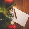 Eine Weihnachtskarte, daneben Kerzen und grüne Zweige, darauf ein Stift.