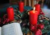 Adventskranz mit einer brennenden Kerze; daneben liegt das Evangelische Gesangbuch mit der aufgeschlagenen Nummer 17 Wir sagen Euch an de lieben Advent.