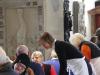 Regionalbischöfin Gisela Bornowski mit Vesperkirche-Schürze beugt sich als Gastgeberin freundlich zu Gästen am Tisch, die in der Kirche sitzen.